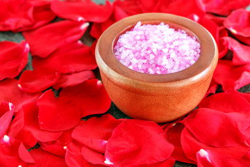 Obraz na płótnie Canvas Sea salt in wooden bowl on petals of rose background. Beauty concept.