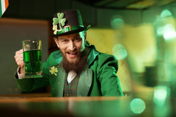 Dark-haired bearded young man in a leprechaun hat with shamrock looking funny