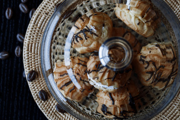 Cake profiteroles with butter cream and chocolate against a dark background. Soft focus.