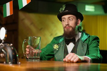 Dark-haired bearded young man in a leprechaun costume looking thoughtful