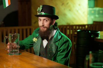 Dark-haired bearded young man in a leprechaun costume looking pleased