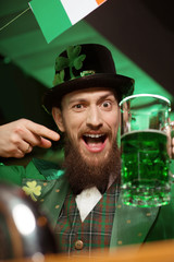 Dark-haired bearded young man in a leprechaun costume looking funny