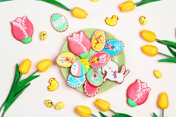 Easter homemade gingerbread cookies on the plate on a light background with tulips.