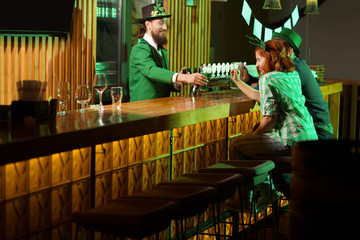 Dark-haired bearded young man in a leprechaun hat having good time with his friends