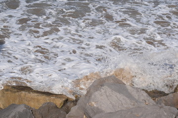 the water foam on the beach splashing the stones