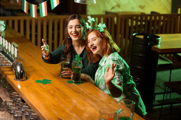 Red-haired pretty girl in a green checkered shirt and a girl with long earrings looking joyful