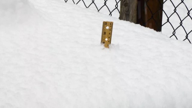 snow falling down on 12 inch ruler on outdoor table