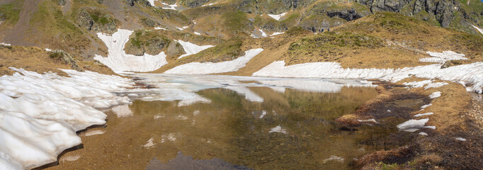 Aerial view of an Alpine natural lake during spring season. Snow melting. Italian Alps. Italy