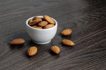almond nuts in wtihe bowl and scattered on the black wooden table