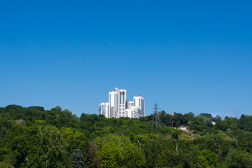 Fototapeta na wymiar Multi-storey houses on a high hill against a blue sky.
