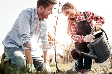 Smiling beautiful small lady watering new tree © Viacheslav Yakobchuk