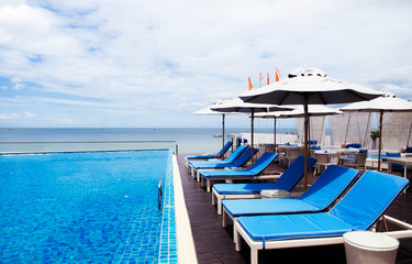 Beach side pool with beach bed and white umbrellas