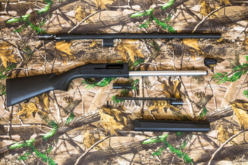 disassembled shotgun parts on the camouflage background