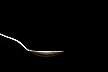 hot steel spoon on black background with steam from water