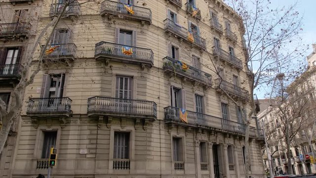 BARCELONA, SPAIN - FEBRUARY 2019. Autumn panorama of a house in Barcelona with balconies on which are placed the flags of Catalonia. The concept of separatism and detachment from Spain in Catalonia