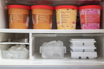 Full of bucket container ice creams flavors and ice cubes in freezer get ready for summer.