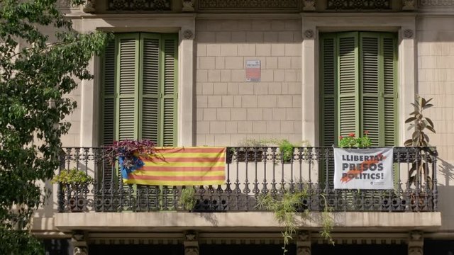 BARCELONA, SPAIN - FEBRUARY 2019. Close-up. Balcony with closed shutters on the house in Barcelona where the flags of Catalonia and protest posters are placed. The concept of separatism and detachment