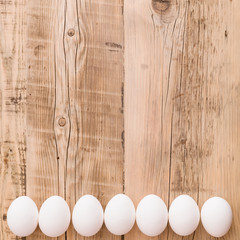Top view on fresh eggs on natural wooden table. Easter festive background. Celebration concept