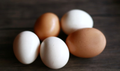 Chicken eggs (brown) and kampong chicken eggs (white) on wood background. Description