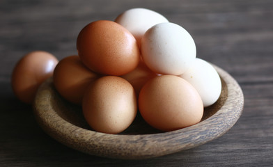 Chicken eggs (brown) and kampong chicken eggs (white) on wood plate.