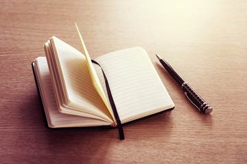 Fototapeta premium Black opened notebook and pen on the table on left top view. place to write