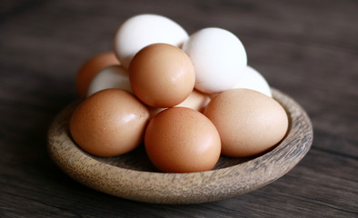 Chicken eggs (brown) and kampong chicken eggs (white) on wood plate.