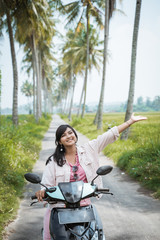 Obraz premium summer scooter ride. asian women enjoy riding her motorcycle in tropical country road