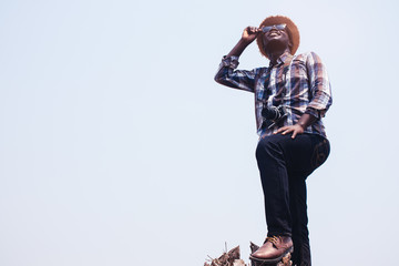 African man photographer Standing holding sunglasses and film camera on the dry tree.