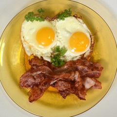 Dish with eggs and bacon and a little parsley.