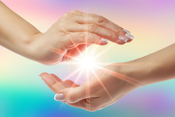 Healing hands with bright sunburst on rainbow background - obrazy, fototapety, plakaty