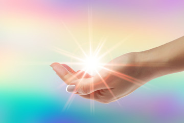 Healing hands with bright sunburst on rainbow background