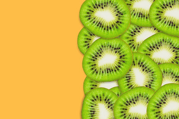 Lot of pieces of sliced tasty beautiful ripe fresh kiwi fruit scattered on orange table in kitchen....