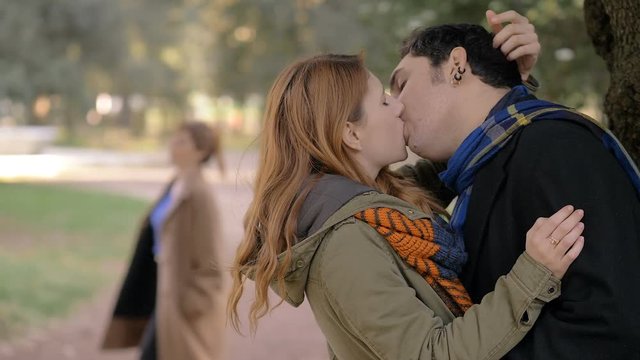 woman finding her husband kissing another young woman in the park.betrayal, lies