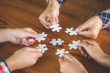 Hands of diverse people assembling jigsaw puzzle, Youth team put pieces together searching for right match, help support in teamwork to find common solution concept, top close up view