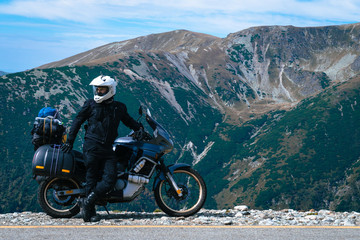 Motorcyclist man and Adventure Motorbike on the top of the mountain. Motorcycle trip. World...