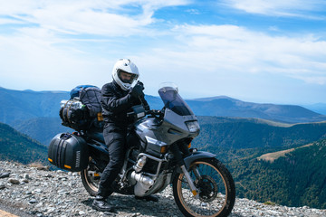 Fototapeta na wymiar Motorcyclist man use smartphone and Adventure Motorbike on the top of the mountain. Motorcycle trip. World Traveling, Lifestyle Travel vacations sport outdoor concept, copy space. Transalpina Romania