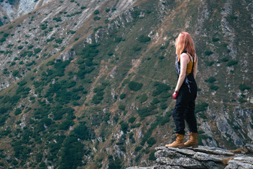 Obraz premium Winner. Success concept. Hiker girl in motorcycle pants after hiking to mountain top. copy spase. adventure Transalpina Romania