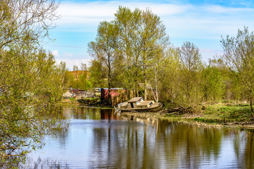 Sunny may day on the banks of the Izhora river. Abandoned boats and boats.