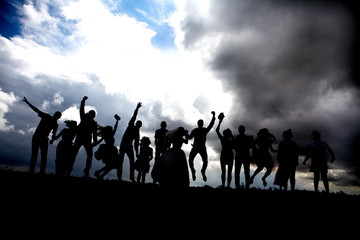 Silhouettes of a group of young people jumping against the sky
