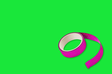 Fototapeta na wymiar Roll of violet sticky tape in corner on green background with copy space for your text