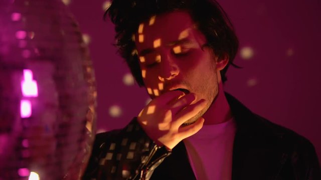 Relaxed man taking ecstasy pill near disco ball dancing in club party atmosphere