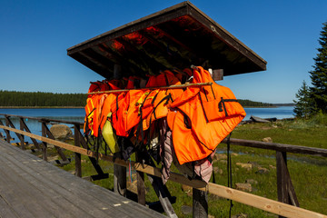 Many orange life vests hanging near the boat station.