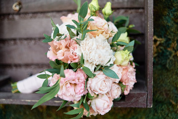 Close up of beautiful lush bridal bouquet of pink and white roses, eustoma and ruscus with satin ribbon in wood box, copy space. Wedding, birthday, holiday concept
