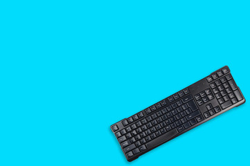 One black plastic wireless computer keyboard on blue office table. Top view. Copy space for your...