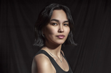 Fototapeta premium Portrait of a beautiful Asian girl in a T-shirt on a black background