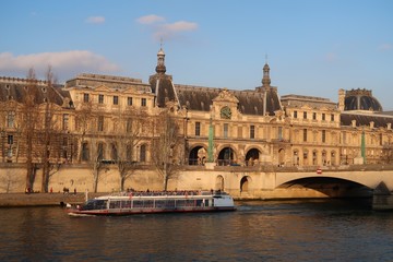 Obraz premium Paris, vue sur le palais du Louvre et la Seine, avec un bateau mouche (France)