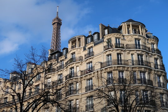 Immobilier à Paris, façade d'immeuble haussmannien et vue sur le sommet de la tour Eiffel (France)