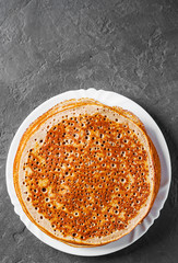 Stack of kefir pancakes in white plate on Dark grey black slate background
