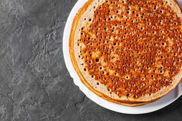 Stack of kefir pancakes in white plate on Dark grey black slate background