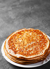 Stack of kefir pancakes in white plate on Dark grey black slate background